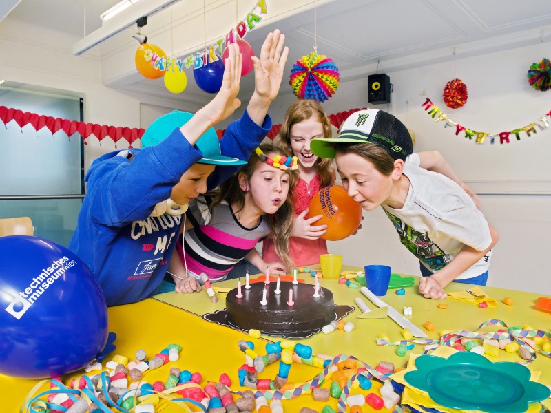 Kinder feiern Kindergeburtstagsparty im Partyraum mit viel Dekoration und Torte : 